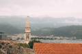 Old medieval town stone houses with red roofs and church bell towers. Budva is the center of tourism in Montenegro and a summer vacation destination. Aerial drone cityscape in Montenegro.