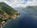 Resort town among green trees on a mountainside by the sea. Dobrota, Montenegro. Drone